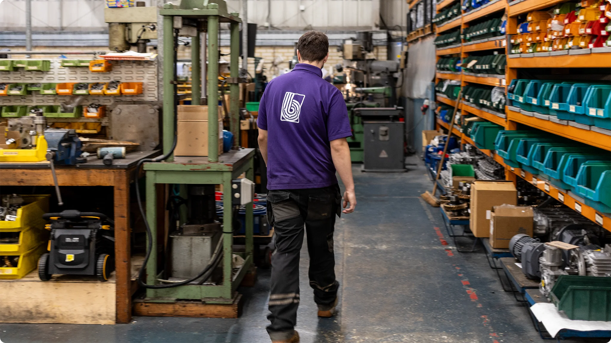 A Brown GearTech worker wearing a branded company polo shirt in the workshop